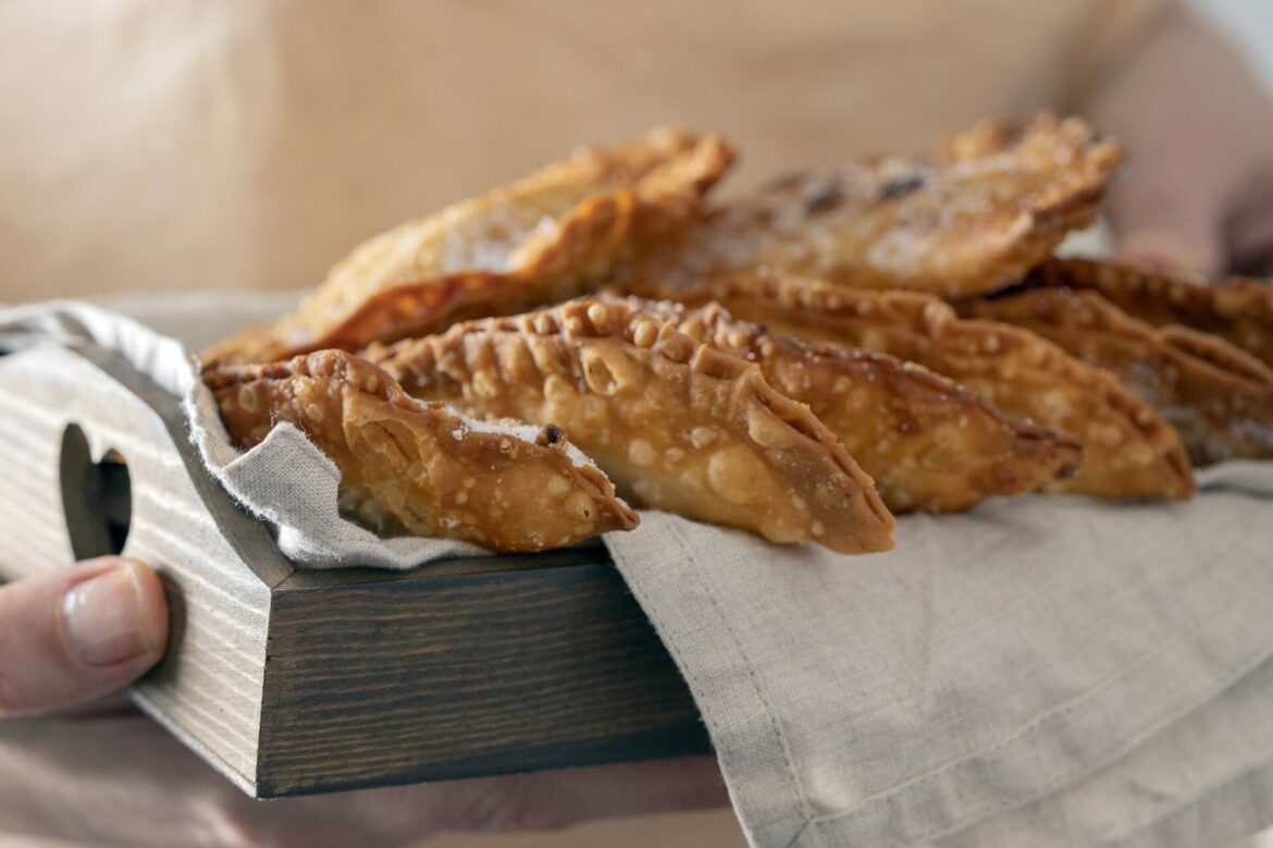 Female hand holding wooden try with Trucha, typical sweet consumed in Canary Islands during the Christmas time.